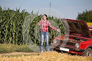 Girl on the phone beside broken car