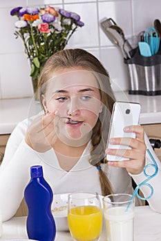 Girl with phone having breakfast in kitchen