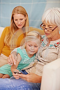 Girl, phone and social media at a home with grandmother, family and mother together with game. Learning, online and