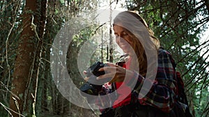 Girl with photo camera standing in forest. woman holding professional camera