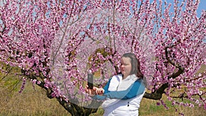 The girl is photographed against the background of a blossoming tree.