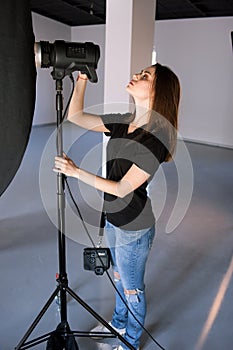 Girl photographer adjust light in studio