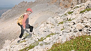 Girl photographer goes up the hill uphill against the backdrop of cliffs of a plateau and the sky with clouds. Concept