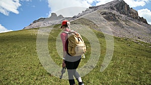 A girl photographer goes up the hill uphill against the background of rocks and sky with clouds. Concept photo tours for