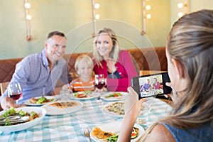 Girl photographing family through mobile phone