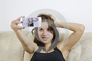 Girl photographing selfie herself with cell phone at home