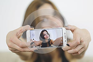 Girl photographing selfie herself with cell phone at home