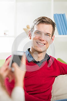 Girl photographs her boyfriend in the living room.