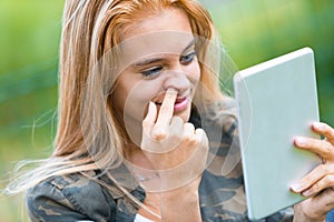 Girl picking her nose and watching a tablet