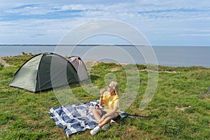 A girl on a picnic near a tent in nature by the sea on the cliff of Paldiski in the summer