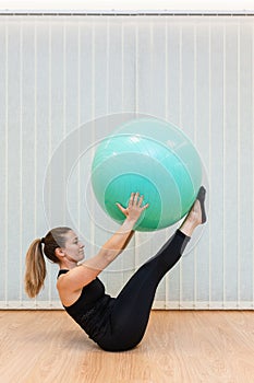 Girl pilates trainer does V fitball posture in fitness center