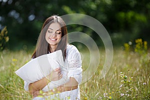 The girl with a pillow on the fresh spring grass.