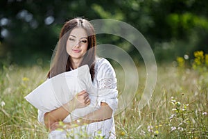 The girl with a pillow on the fresh spring grass.