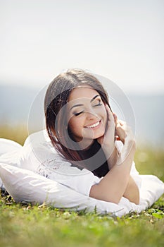 The girl with a pillow on the fresh spring grass.