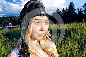 Girl pilot in a flight helmet is in the summer on a background of green grass in Sunny day