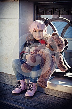 Girl in a pink beret holds a toy bear