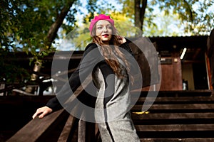 A girl in a pink beret is standing on a wooden staircase