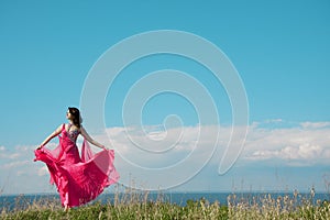 Girl in pink dress against the backdrop of sky.