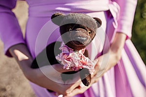Girl in a pink dress holding a Teddy bear in her hands. Girl says goodbye MS childhood. A woman in a beautiful pink dress and a