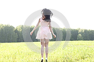 The girl pink dress is jumping meadow summer, happiness concept idea of fun, relaxation figure sun joy