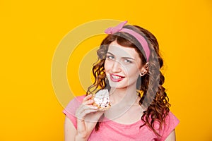 Girl in pink dress pinup-style eats cake with cream