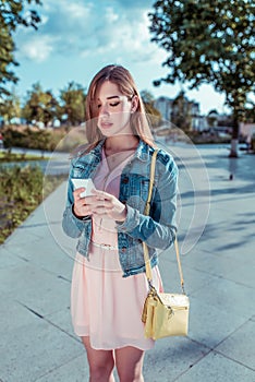 Girl pink dress, summer city park, holding mobile phone in her hand, reading message, writing text on social networks