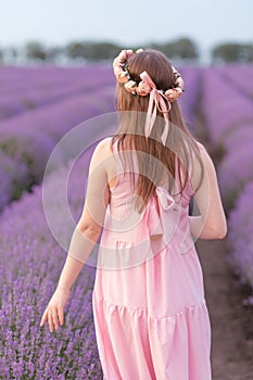 A girl in a pink dress walks on a lavender field