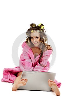 Girl in pink dressing gown sitting with laptop