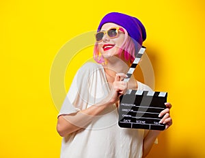 Girl with pink hair holding movie clapper