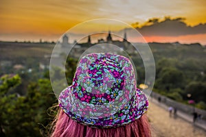 Girl with pink hat and pink hair back to camera on sunset background