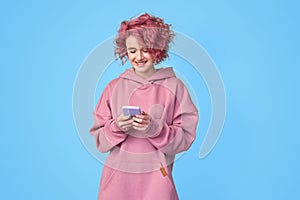 Girl in pink hoodie communicating online or playing on her smartphone