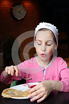 Girl in a pink jacket and a headband eating