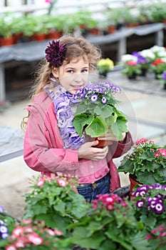 Girl in a pink jacket holding flower pot with