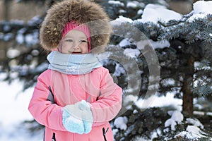 Girl in pink jumpsuit playing in snowballs. wintertime for children. winter games outdoors.