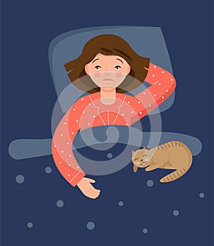 A girl in pink pajamas lies in bed and cannot sleep. Insomnia. The cat lies on the blanket.