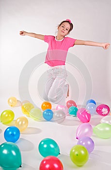 Girl in a pink shirt and jeans jumping in the studio