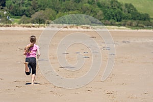 Girl in pink shirt running down the sandy beach