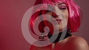 Girl with pink short hair. A model with long pink earrings and makeup. The girl in the video laughs, flirts, poses, dances, touche