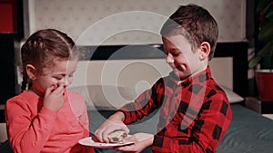 Girl in pink skirt plays with guy in black and red plaid shirt, feeds her cake