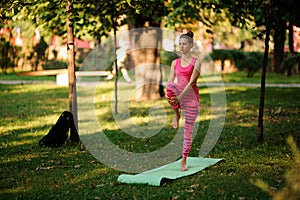 Girl in the pink sportsuit practice yoga in the park