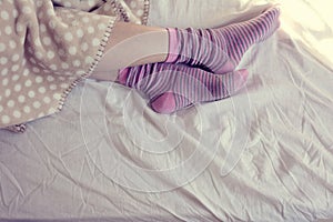 Girl with pink striped socks, sleeping in bed