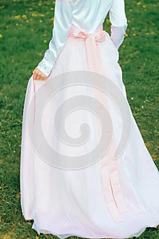 Girl in a pink wedding dress on a background of grass.