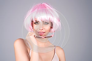 Girl with pink wig. Beautiful young woman with clean fresh skin on studio background. Face care, facial treatment