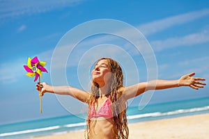 Girl with pinwheel on the beach happy and relaxed