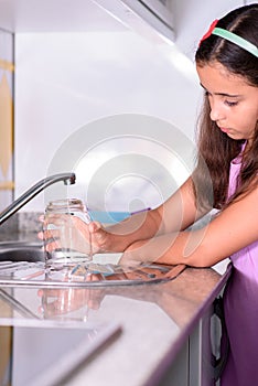 Girl placing a freshly scrubbed glass to dry. Helping with housework. Vertical photography