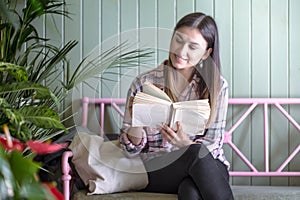 girl in a plaid shirt with eco bag sitting on a bench in the store and reading a book
