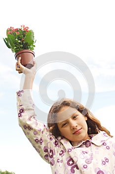 Girl with plant pot against blue sky.