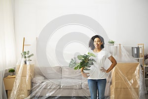 Girl with plant in pot, covered furniture with oilcloth for repair