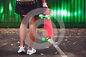 Girl with plastic orange penny shortboard behind green wall in cap photo