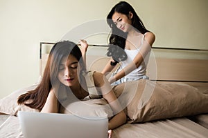 girl play computer and be massaged on bed